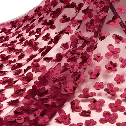 Polyester tulle in Crimson/Maroon. This lightweight tulle has a fine mesh with a layered, sewn applique floral motifs and a textured handle. It has an airy drape with a slight structure to it, semi-sheer coverage, and elongates across the salvage.